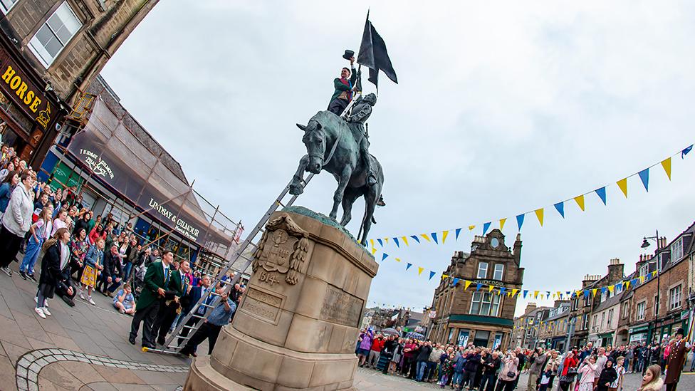 Cornet Greg Middlemass attaches colours to the monument