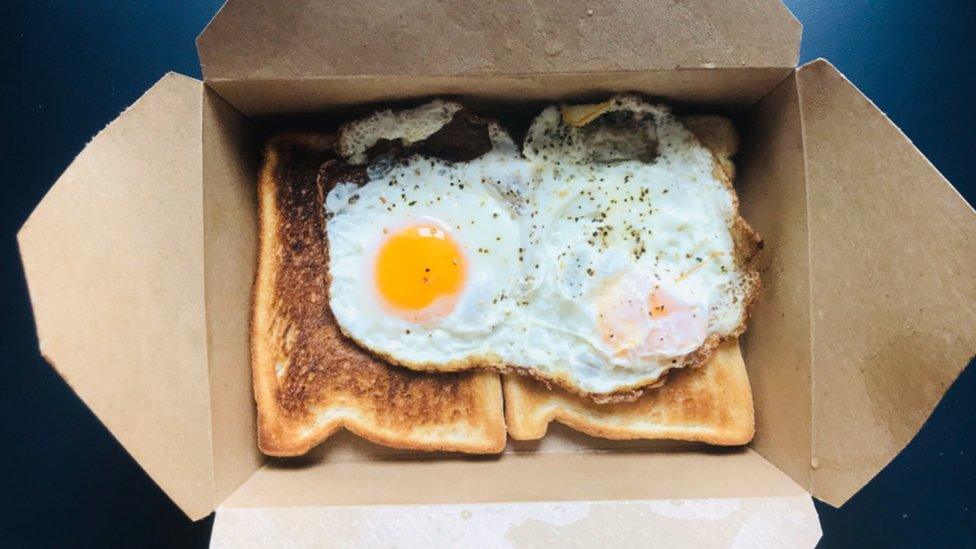 Two eggs on two slices of toast served in a brown cardboard box