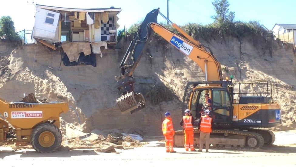 Heavy machinery on the beach clearing debris from collapsed house