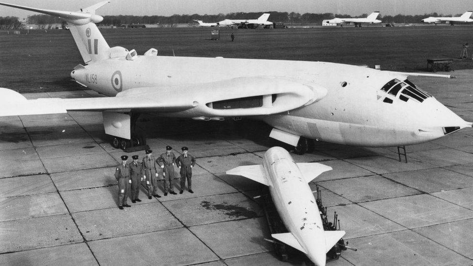 British ground crew stand by their giant Victor Mark 2 as a Blue Steel Stand-Off bomb is about to be loaded into position at RAF Wittering, Northants