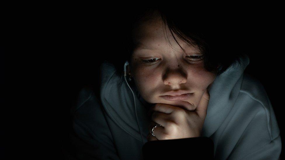 Teenager on phone in dark