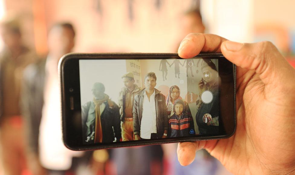 A worker takes a group photo at lost and found camp