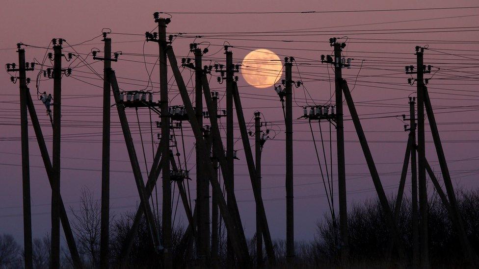 A full moon is seen rising through electric poles near Virbalis, Lithuania February 10, 2017