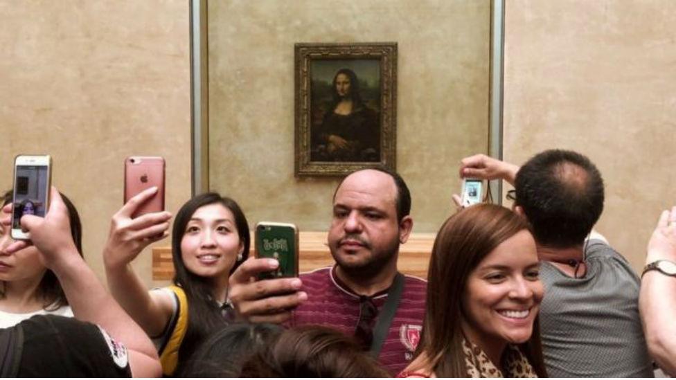 People taking selfies in front of a Painting of Mona Lisa