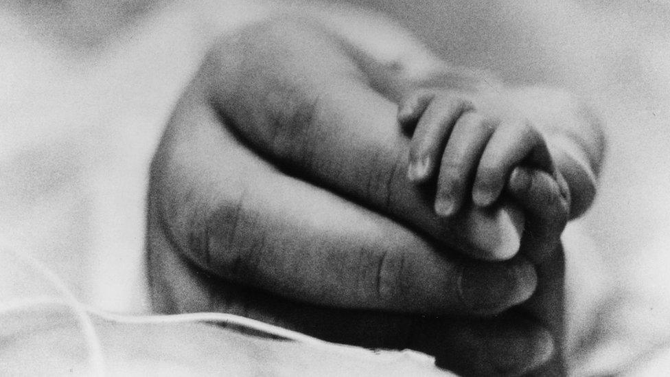 A file photo of a parent holding the hand of a newborn baby