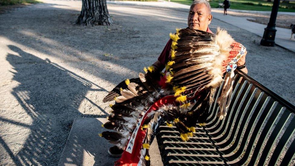 Hanley Frost Sr holding a headdress made with eagle feathers