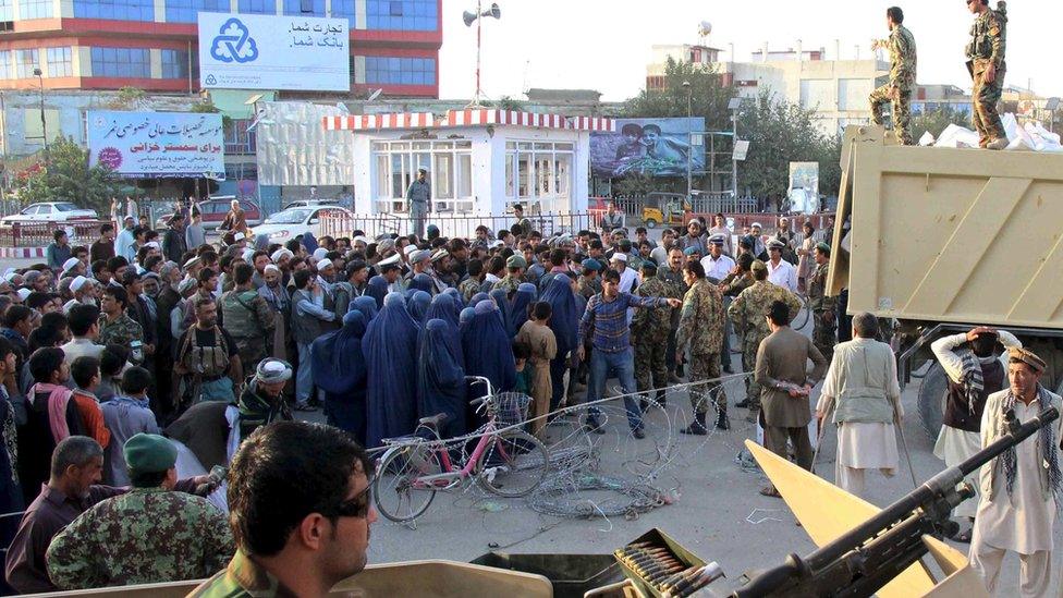 Afghans wait to receive aid distributed by the National Army troops in Kunduz, Afghanistan October 14, 2015