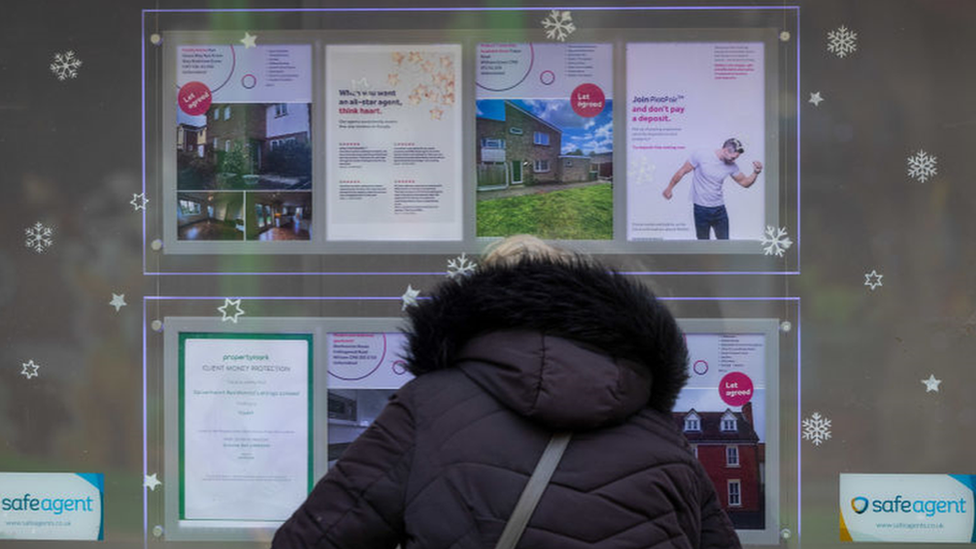 Woman looks in estate agent's window