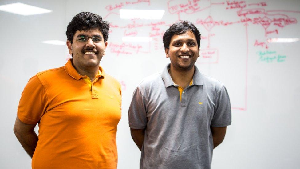 Two men in T-shirts standing in front of a whiteboard