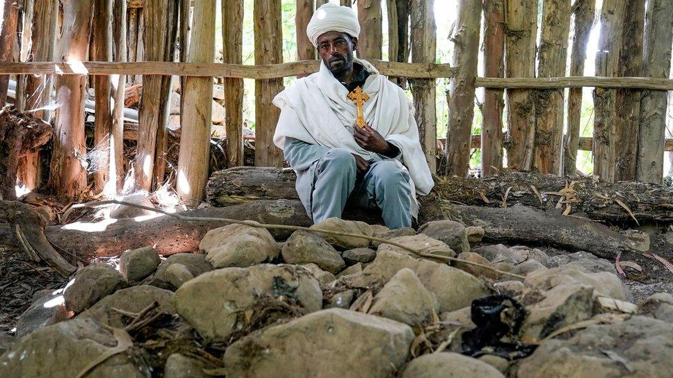 (Priest) Tiftu Ejigu mourns his 40 year old wife and 3 year old daughter at their grave site on the 40th Day commemoration of their deaths at the massacre at Chena Teklehaymanot Church on October 10, 2021 in Chena, Ethiopia.