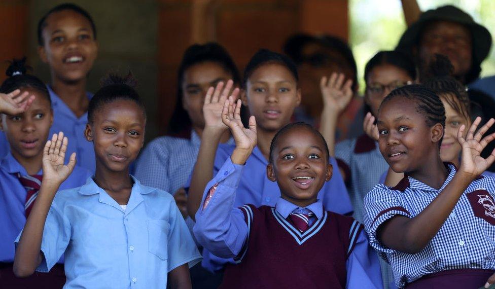 Schoolchildren wave to the camera.