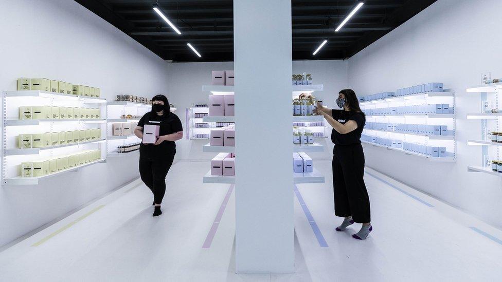 Amy Healey, and Alisha Moore, from Manchester work inside of a shop which is part of an art installation titled EART, by Rashid Rana