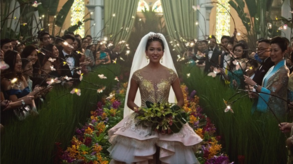 Movie still from Crazy Rich Asians showing Sonoya Mizuno walking down the aisle in a wedding dress