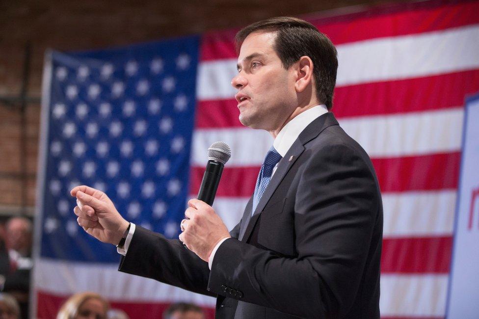 Marco Rubio speaking in front of an American flag