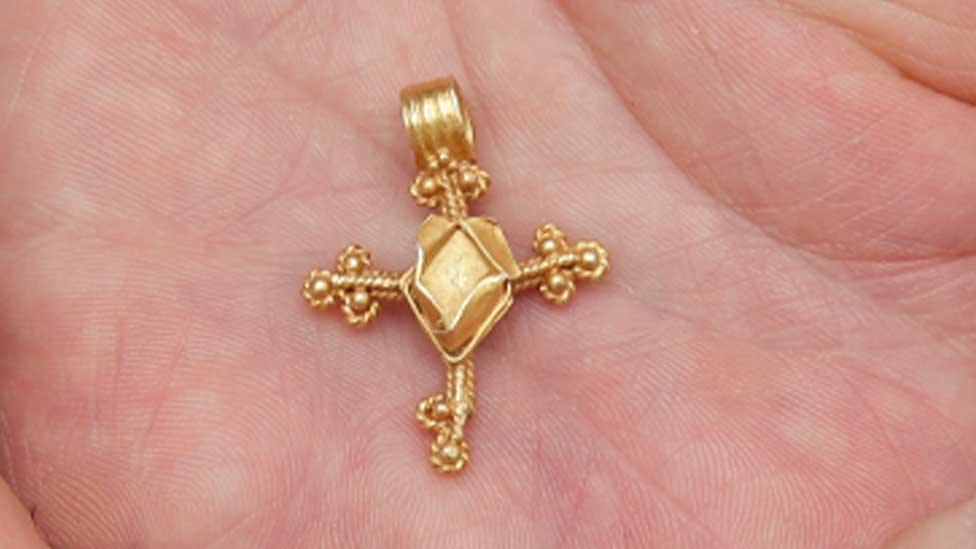 Medieval cross pendant in someone's palm