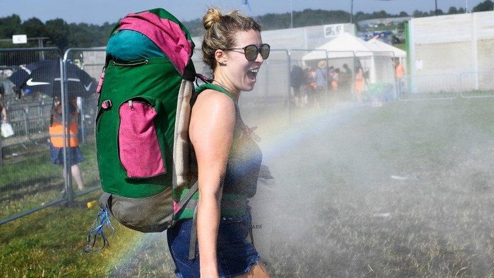 Woman with rucksack being sprayed with water.