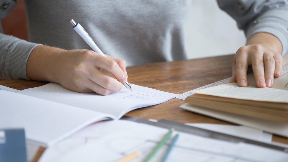 A stock image of someone writing at a desk