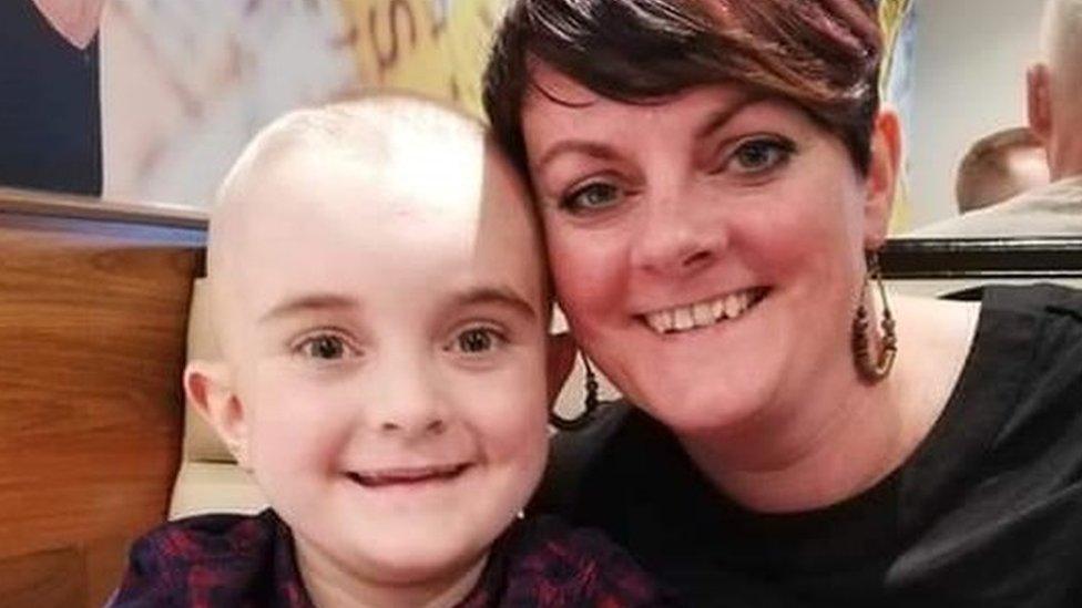 A young boy and his mum smile at the camera