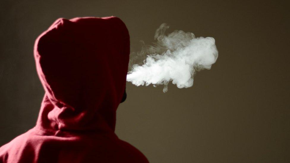 Young man in a hoody vaping