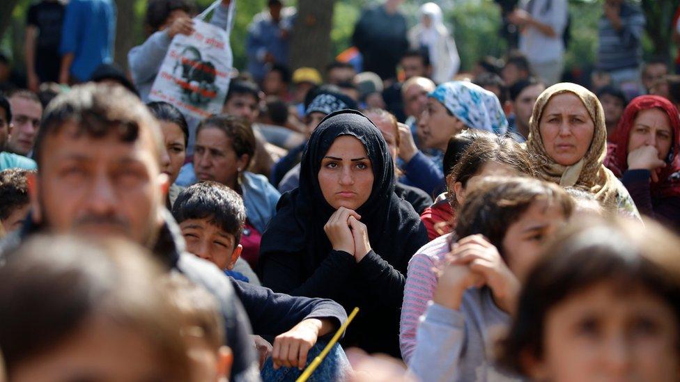 Migrants, mostly Syrians, listen to an Arabic speaker talk to them about their future as they rest in a stadium in Edirne, Turkey, Wednesday, 23 September 2015