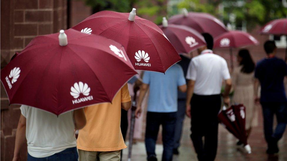 People holding Huawei umbrellas