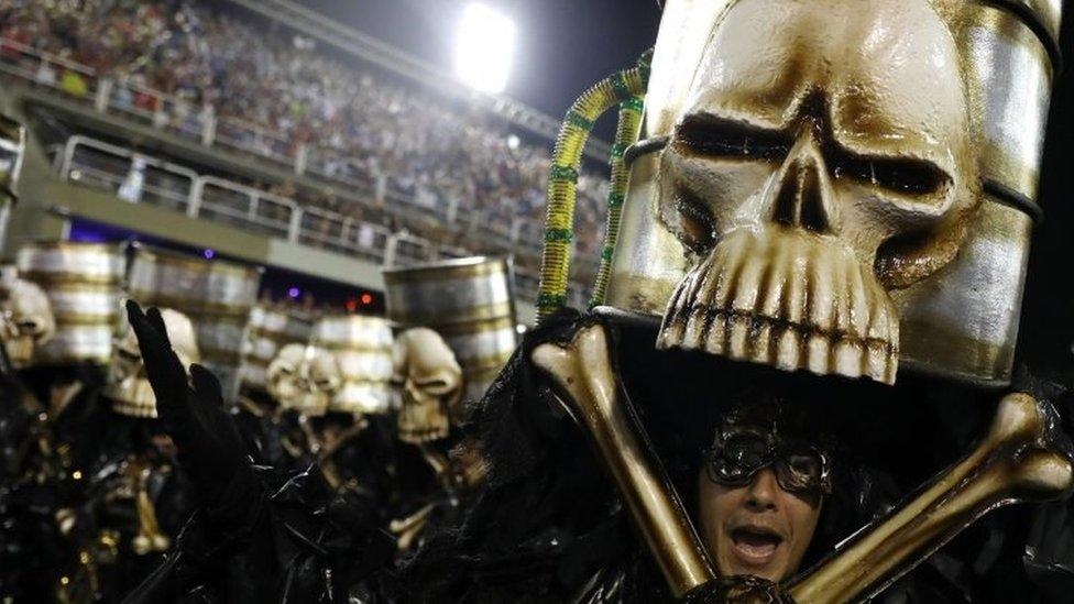 Skull-shaped oil barrels are lifted up at Rio Carnival