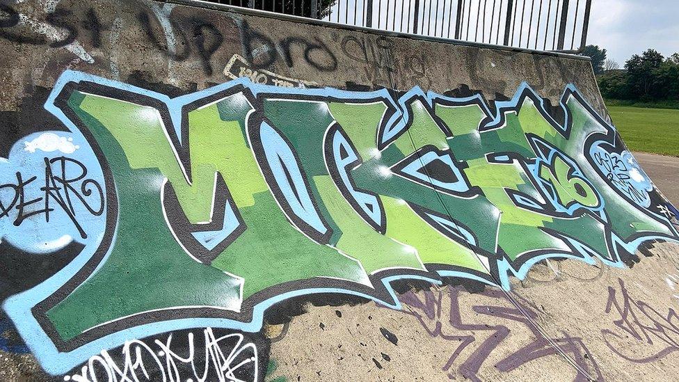 A graffiti tribute reading "Mikey" painted in green on a skateboard park ramp