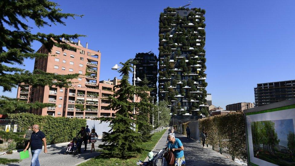 People walk in front of the architectural complex designed by Studio Boeri, the "Bosco Verticale" (Vertical Forest) in Milan