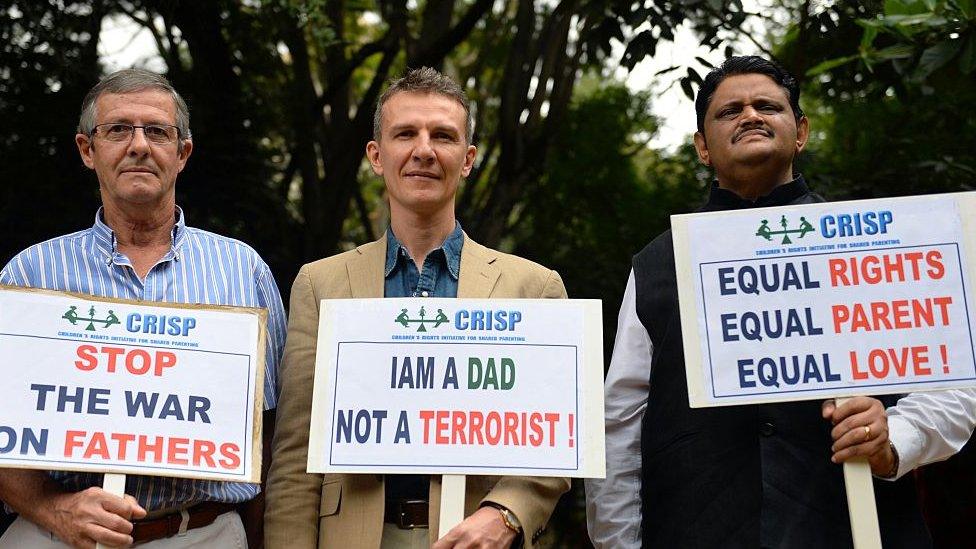 Pascal Mazurier (C), an ex-French consular officer who once worked for the French Consulate in Bangalore, holds a placard along with his father Jack Mazurier (L) after a press conference in Bangalore on June 17, 2015.