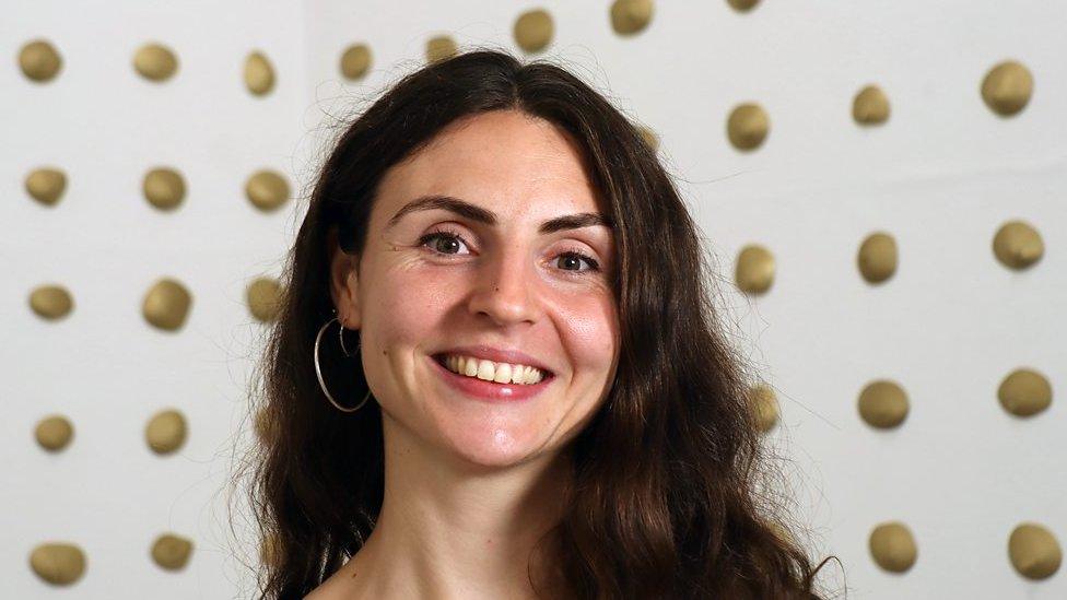 a woman with long dark hair is smiling at the camera