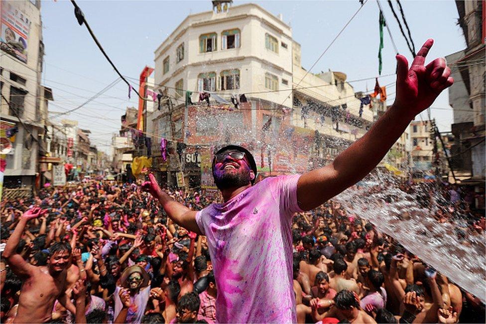 People dance as they throw coloured powder and spray water during Holi celebrations, amid the COVID-19 pandemic, in Prayagraj, India's northern state of Uttar Pradesh on March 30, 2021.