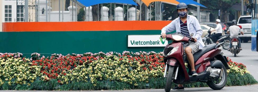 A motorbike waits in front of a sign promoting APEC Summit in Hanoi, Vietnam May 17, 2017