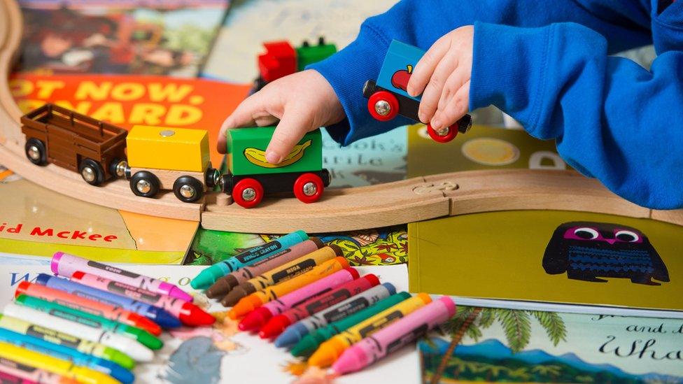 A toddler playing with a selection of children's toys