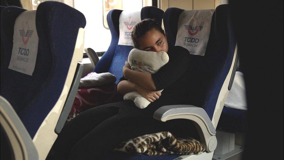 A young girl rests on a train