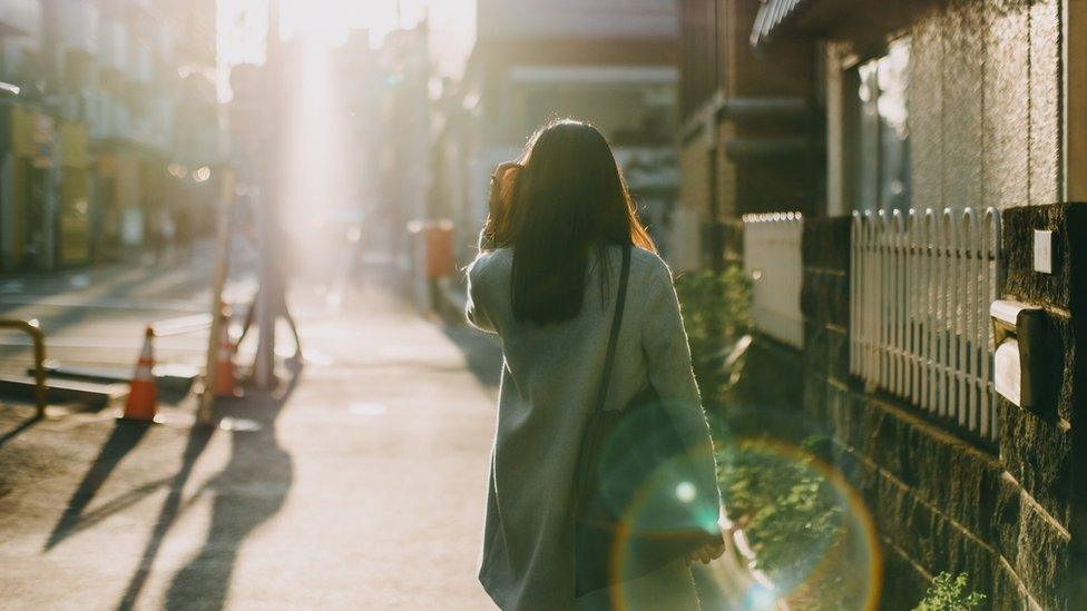 Rear view of a woman walking down the street