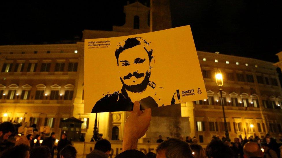 A sign with Regeni's face being held up at a demonstration