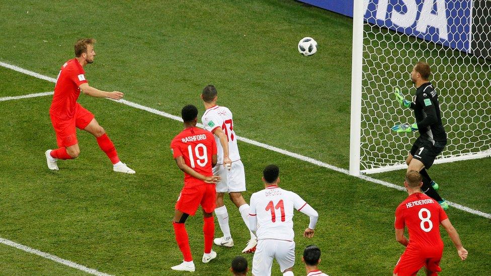 Kane heads the ball towards the Tunisia net.