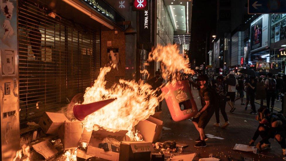 A demonstrator adds to the flames outside a metro station in Hong Kong