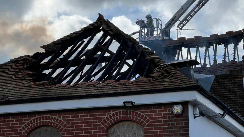 A burnt roof with just the support beams visible after a fire