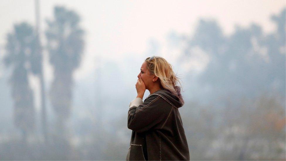 A woman reacts as the Woolsey Fire burns in Malibu, California,