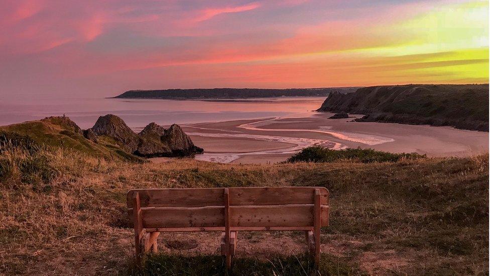 Looking towards an empty bench, the perfect seat to enjoy the sky's rich colours at sunset