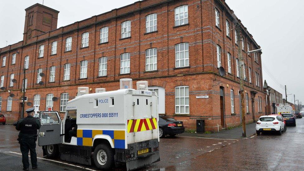 A police officer stands outside the block of flats on Victoria Street in Lurgan where the woman's body was found