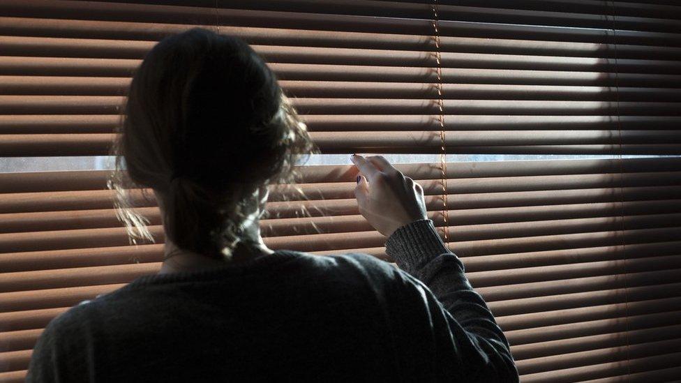 Woman looking through blinds