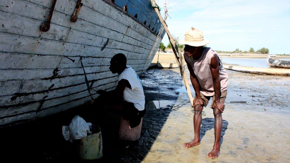 A shipbuilder supervises the work of his son on one of their boats