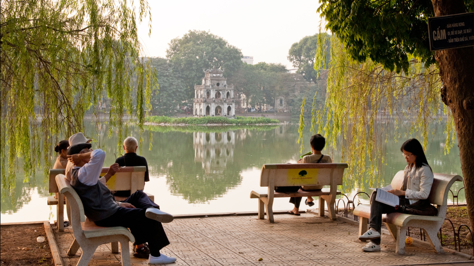 People relaxing on benches by Hoan Kiem Lake