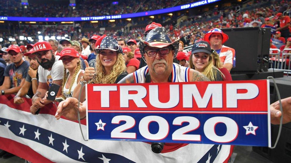 A man holds up a sign as the crowd waits for US President Donald Trump to arrive at a rally at the Amway Center in Orlando