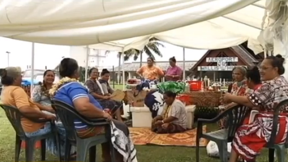 The villagers sitting together at the airport
