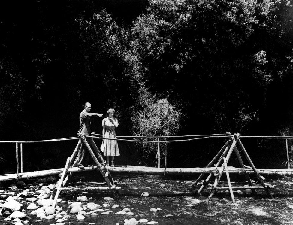 Princess Elizabeth and the Duke of Edinburgh pause on the rustic bridge in the grounds of the Royal Lodge, Sagana, their wedding present from the people of Kenya.