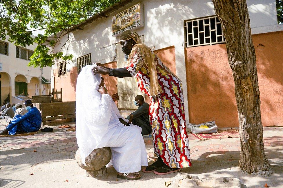 Adja Assisi has her headscarf adjusted by another woman