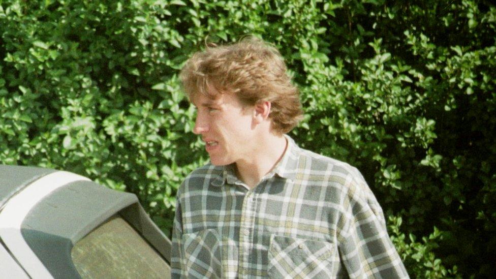 Matthew White, photographed by police surveillance next to a car and in front of a hedge